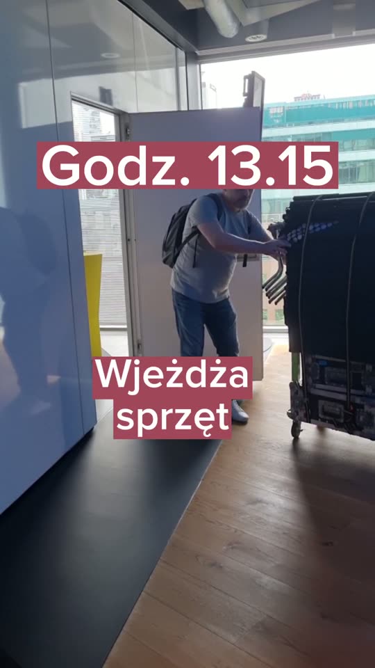 Ekipa wwozi sprzęt nagraniowy na wózku do biurowca klienta